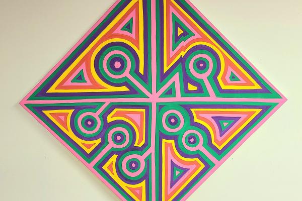 "Initials" by CFW Aguirre. It is a diamond-shaped canvas divided into symmetrical sections, each filled with vibrant and contrasting colors such as pink, yellow, green, and purple. The design features a combination of geometric patterns, including triangles and circles, with circular patterns at the tips of the diamond.