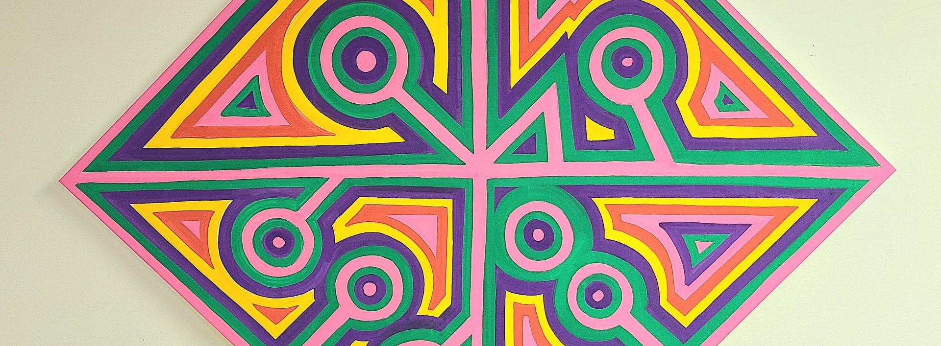 "Initials" by CFW Aguirre. It is a diamond-shaped canvas divided into symmetrical sections, each filled with vibrant and contrasting colors such as pink, yellow, green, and purple. The design features a combination of geometric patterns, including triangles and circles, with circular patterns at the tips of the diamond.